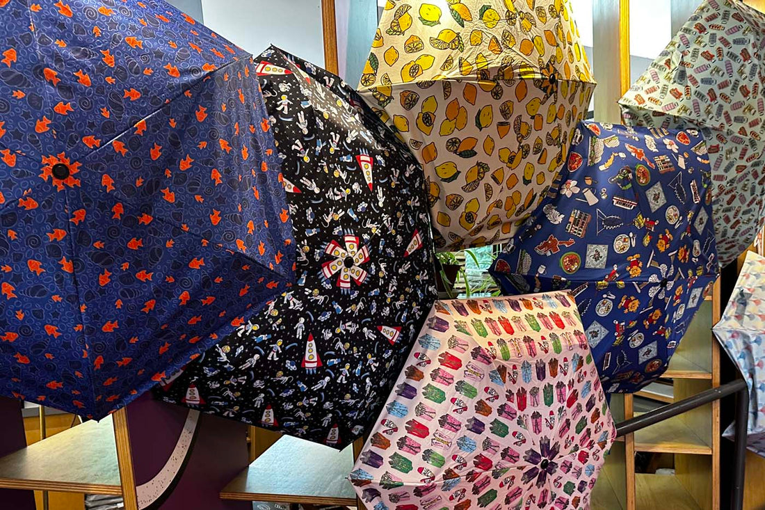 Colorful umbrellas featuring unique, whimsical prints designed by artists on the autism spectrum, displayed at The Art Faculty store in Enabling Village.